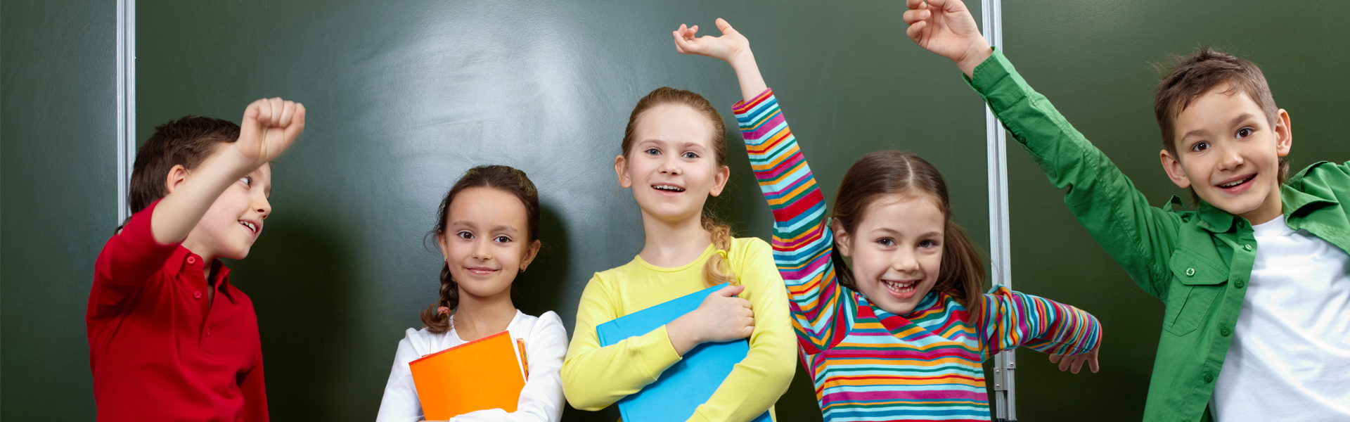Children raising hands and smiling in a classroom at Fueling Brains Academy, preschool in Calgary.